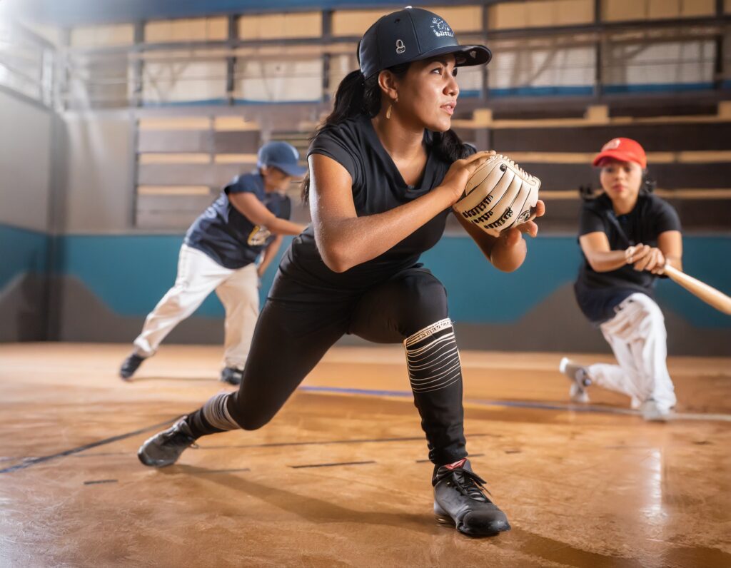 players playing baseball game in an indoor sports court with brown flooring; shallow depth o